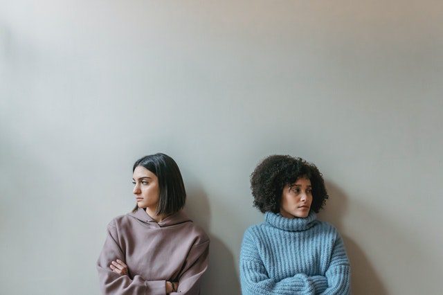 couple sitting against wall looking away from one another